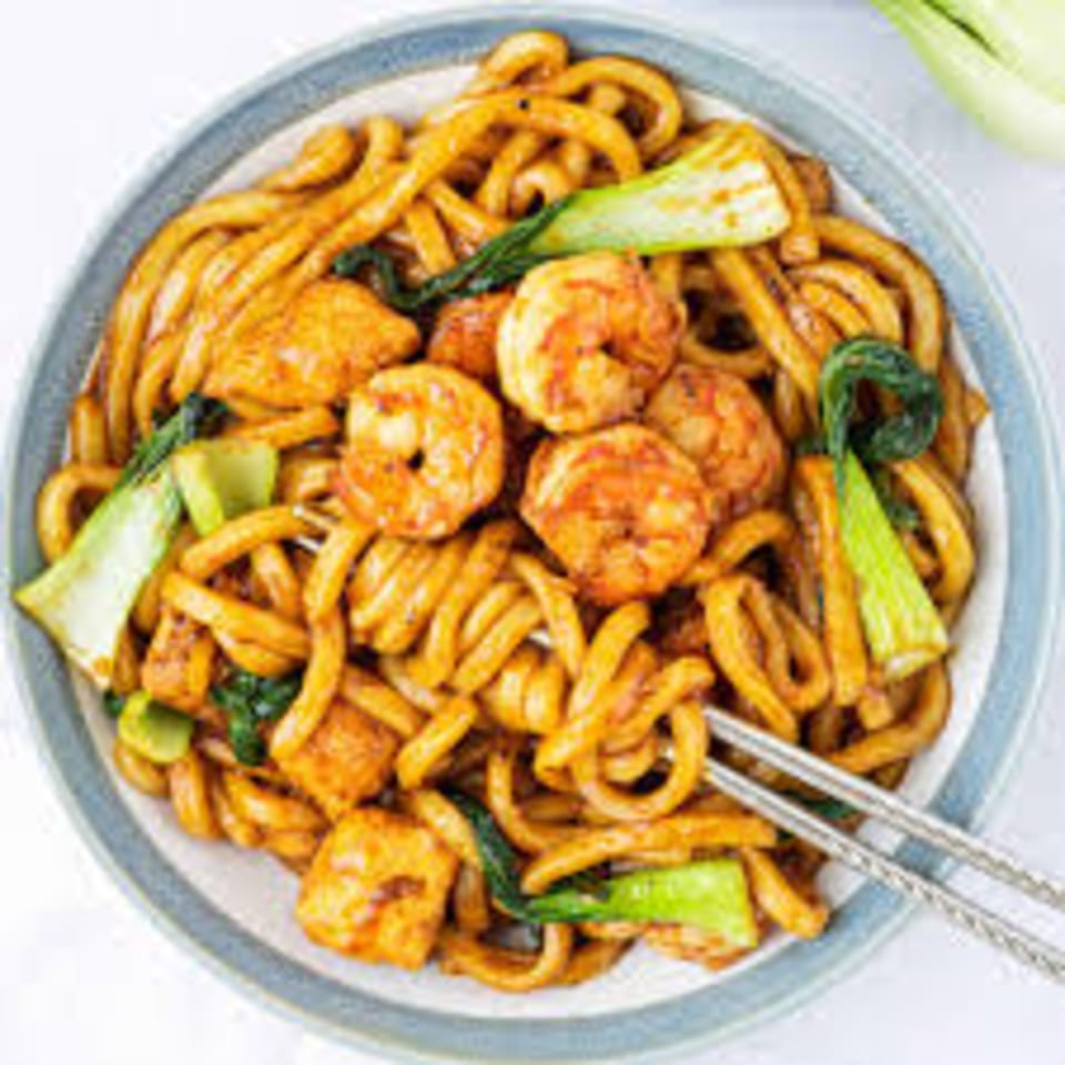 Japanese udon noodles with shrimp, tofu, and bok choy, served with chopsticks.