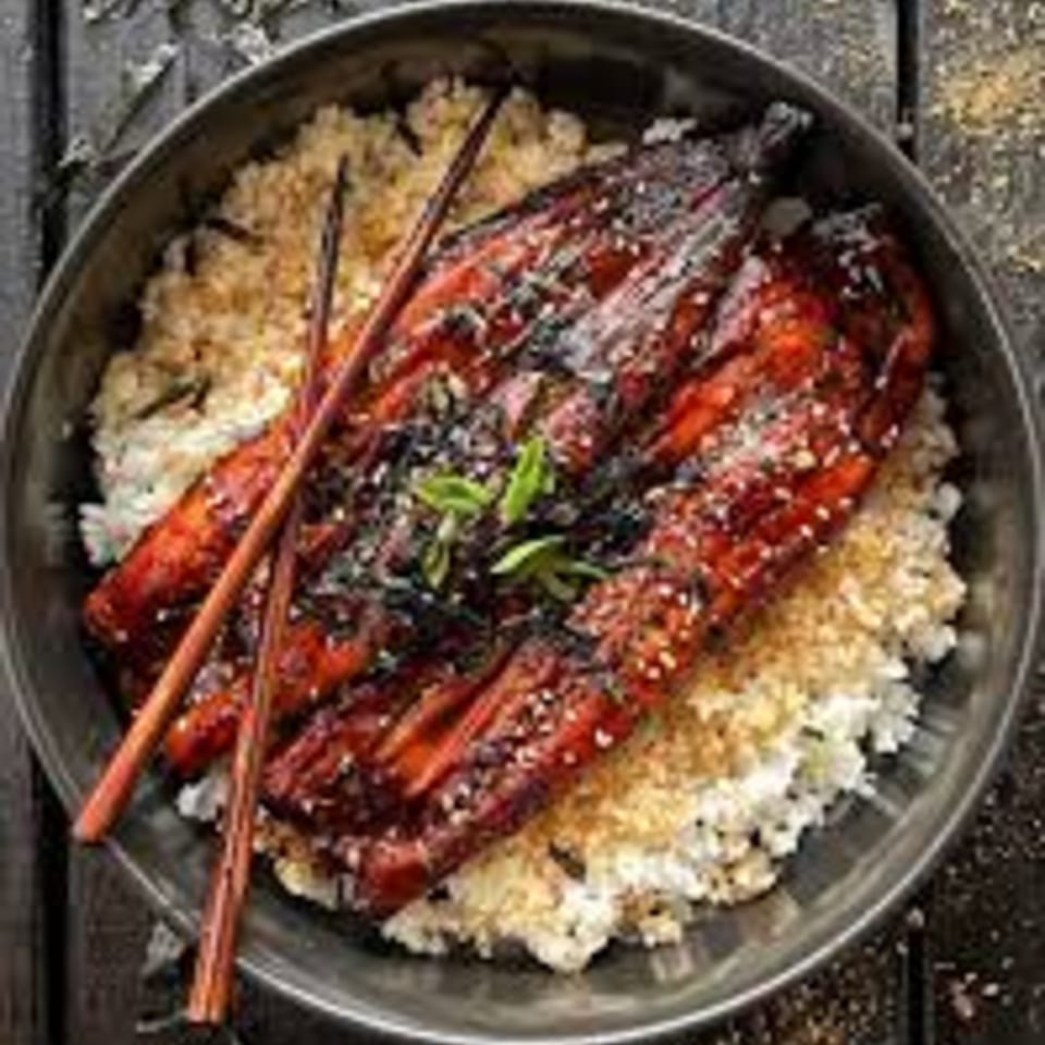 KENICHI BENTO's Unagi Donburi features grilled eel over rice, garnished with sesame seeds and green herbs.