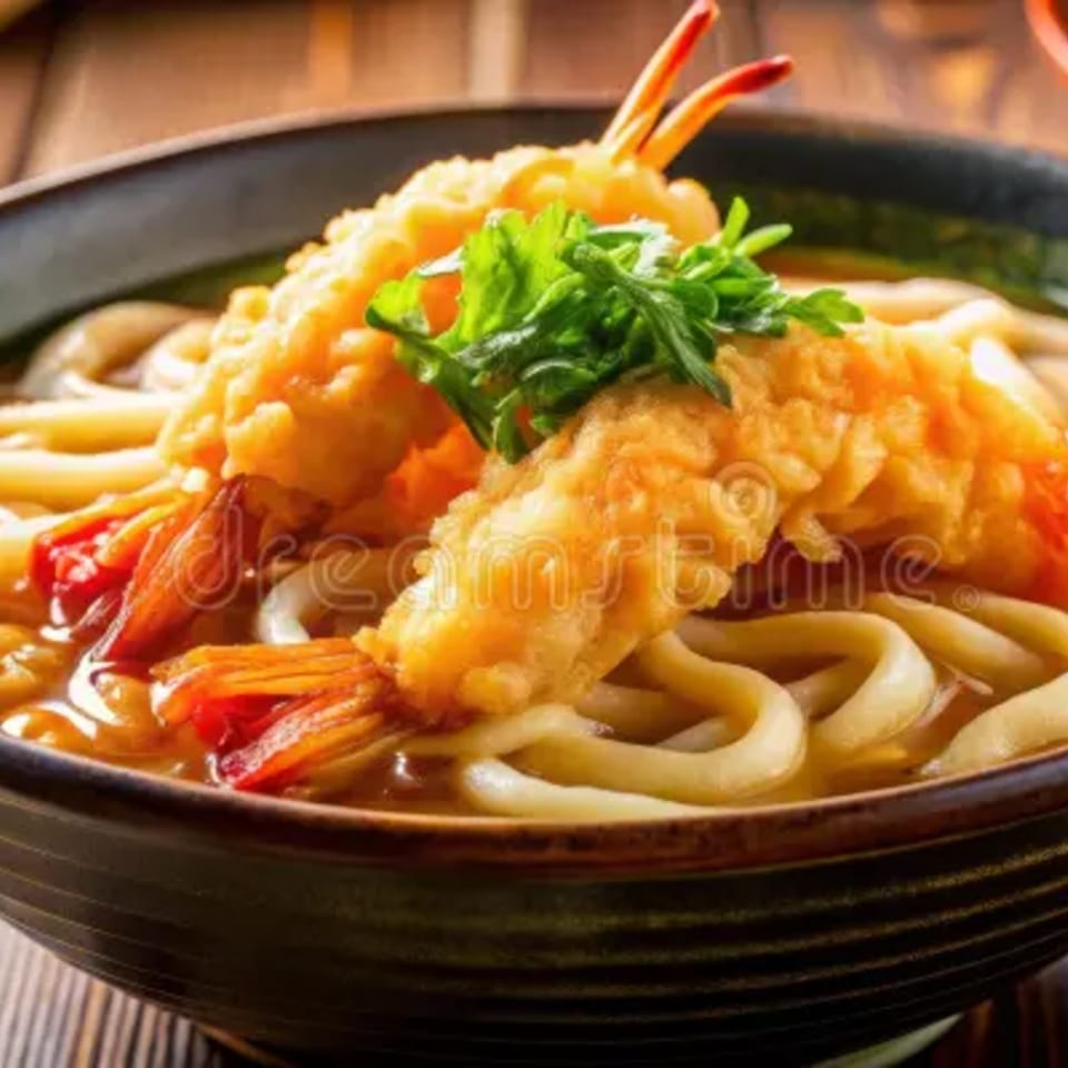 Tempura shrimp and fresh greens garnish a bowl of Kenichi Bento's Japanese udon noodles.